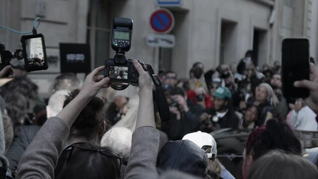 Paparazzi photographing celebrity arrival on city street