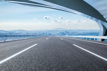 Fototapeta premium Empty asphalt road and bridge with city skyline background