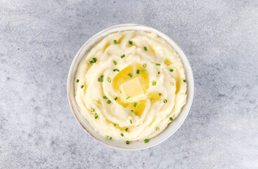 Champ mashed potatoes with green onions in white plate on grey background, top view.