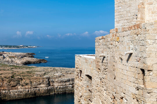 Panoramic high level view of historic brick building at the cove Lama Monachile and the further coastline near Polignano a Mare, Italy known for clear water and pebble beach