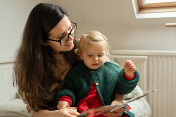 Loving Mother in Her 40s Reading a Book to Her Toddler Daughter at Home. High quality photo