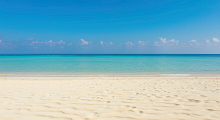Fototapeta premium Pristine white sand beach with crystal clear turquoise ocean water under bright blue sky. Tropical paradise destination. Summer vacation getaway. Natural coastal landscape. Relaxation retreat