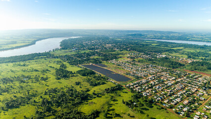 Aerial panorama of a solar power plant next to a small town and river, showing integration of renewable energy into the local landscape.