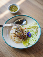 Thai street food. Top view of fried rice with dried Gourami Fish on the wooden table, window lighting. Thai local food dish and blur fish sauce chili on the background.