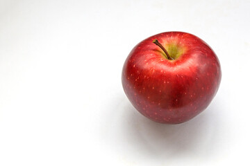 A red apple with a stalk. The skin is covered with many small yellow dots.