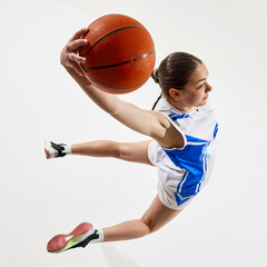 Aerial view. Dynamic photo of young girl basketball player jumping in motion score goal against...