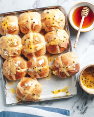 Homemade hot cross buns with passion fruit honey glaze