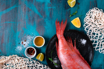 Beaked redfish or perch prepared for cooking a meal with other ingredients around on the blue...