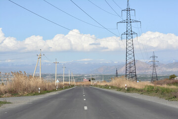 High-voltage power lines on the road in the mountains. Road and electric powers
