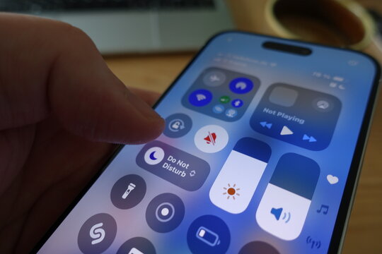 Kiel, SH, Germany, 04-24-2025: Hand interacting with the iPhone&rsquo;s Control Center, featuring the Do Not Disturb function and various connectivity icons