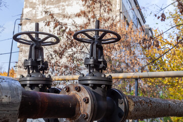 Close-up of shut-off valves on street central heating pipes. Huge industrial black valves on the heating main. Heating season in the city