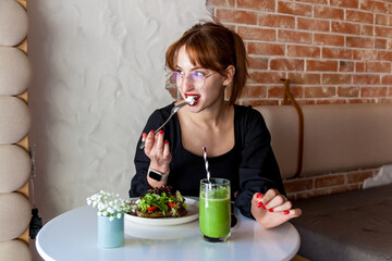 Woman enjoying healthy meal with green smoothie in cozy cafe