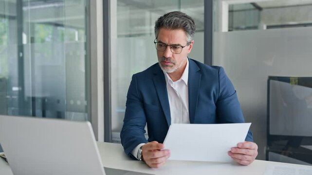Busy financial specialist senior man working with finance sales document report and pc laptop computer in office. Mature executive businessman professional doing analysing paperwork, business review 