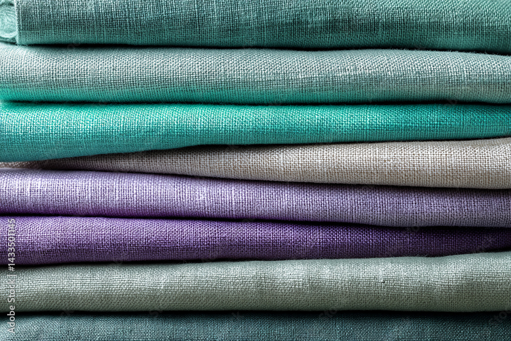 Poster stack of linen fabric in muted pastel shades, showcasing texture and color variations. represents ca