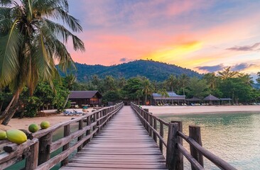 Fototapeta premium Wooden bridge to the sea at tropical beach resort with colorful sunset, pier for swimming and boating in summer, Thailand.