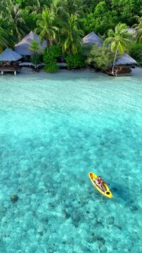 woman in a bikini relaxes on a yellow kayak floating on clear turquoise sea, top-down view from above, peaceful moment in tropical paradise, summer holiday, maldives, travel, holidays, vacation