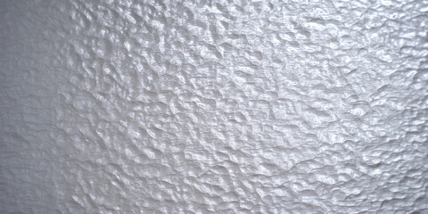 Textured, rippled surface with an irregular pattern of light and shadow, resembling frosted glass or ice.  