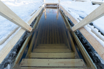 ice hole in a frozen lake with steps for descent, winter hardening and winter swimming