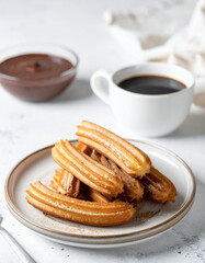 Tasty churros with chocolate in plate on cafe table. Spanish sweet pastry. Delicious food.