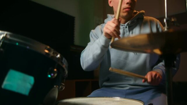 A drummer enjoying their hobby, playing energetically in dark room, expressing passion and relaxation through rhythmic beats. Drums as hobby for man with white hair. Creative musician play on drums.