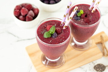 Raspberry blueberry smoothie with chia seed and fresh mint on white kitchen table. Healthy summer...