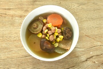 boiled corn with peanut and slice vegetable topping mushroom in Chinese herb soup on bowl