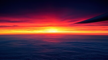 A sunset view through the airplane window with wing in sight.