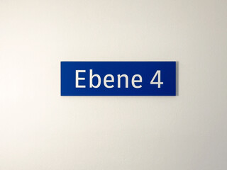Blue floor sign ebene 4 on white wall indicating level number