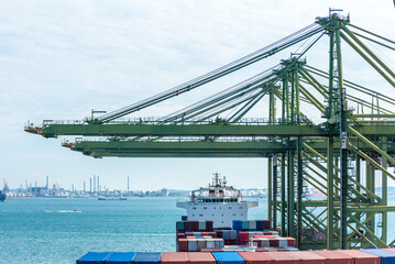 Gantry cranes over a cargo container ship in the port of Singapore. Cargo operations in process. 
