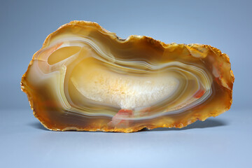 Polished banded agate slice with translucent chalcedony and natural crystal texture on neutral background