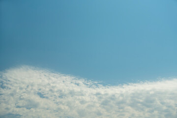 Soft, textured white clouds spread across the lower portion of a clear, bright blue sky