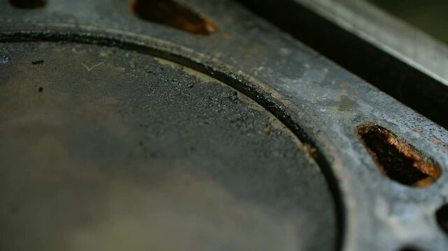 Worn piston surfaces coated with deposits reflect engine degradation; corroded cylinder head shows mechanical fatigue in aged motor parts. Macro footage. Close-up of deposits on piston of car motor.