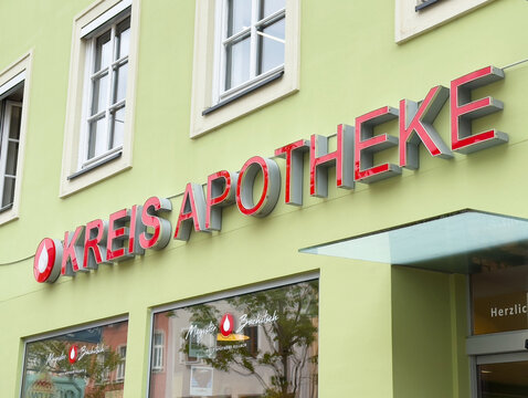 Modern kreis apotheke facade with red signage on light green building