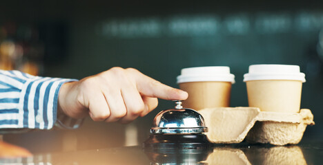 Person, hands and bell with coffee for service, customer attention or signal on cafe counter. Closeup, consumer or touch with ring for hospitality, staff or help at shop, restaurant or cafeteria