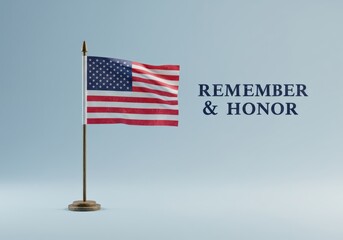 Fototapeta premium A small American flag waves, with the words 'remember & honor' beside it against a soft, light-blue background.