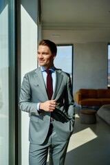 Professional man enjoying a moment of reflection by the window on a sunny day in a modern urban apartment