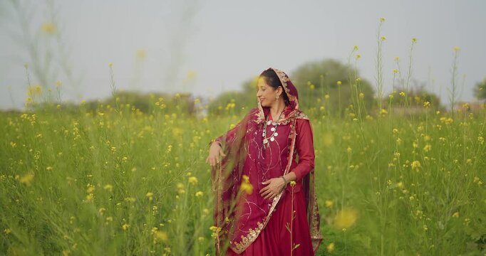 Indian happy adult gen x model woman lady wear red saree walking enjoy outdoor nature asian smiling relax female looking at camera pluck yellow flower in air desi life