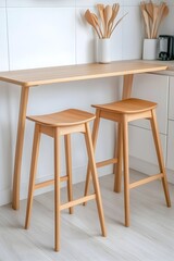 Two light wood counter stools sit beside a matching wooden counter  Utensils are visible in a vase