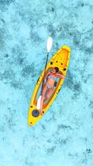 woman in a bikini relaxes on a yellow kayak floating on clear turquoise sea, top-down view from above, peaceful moment in tropical paradise, summer holiday, maldives, travel, holidays, vacation