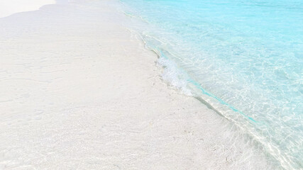 Top view of tropical beach with white sand and clear blue ocean turquoise water in natural sunlight, minimalist peaceful scenery background, relaxation, hotel, summer escape, Maldives island vacation