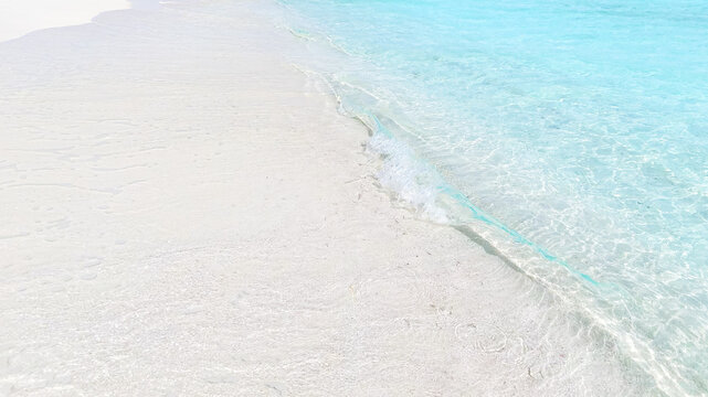 Top view of tropical beach with white sand and clear blue ocean turquoise water in natural sunlight, minimalist peaceful scenery background, relaxation, hotel, summer escape, Maldives island vacation