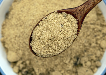 Organic Brown Sugar Spoon: Close-up view of a wooden spoon holding a spoonful of organic brown sugar, with a larger quantity of the same sugar in the background.