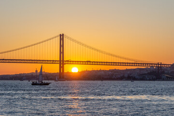 25th of April Suspension Bridge, Sailboat and Tagus River at Sunset. Lisbon, Portugal. View from Cacilhas