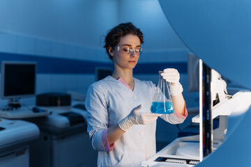 Woman with medical research, chemistry laboratory and science for pharmaceutical. Development Center. Scientist in goggles holding blue chemical liquid into test tube analysis. Medicine concept