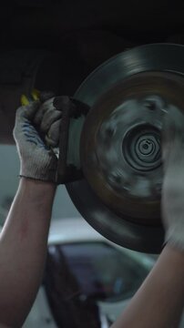 A car mechanic repairs the brake system of an old car.