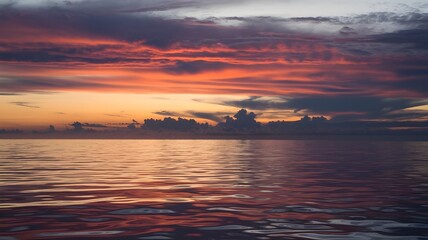 Obraz premium Dramatic sunset over the ocean, vibrant colors painting the sky and reflecting on the water.