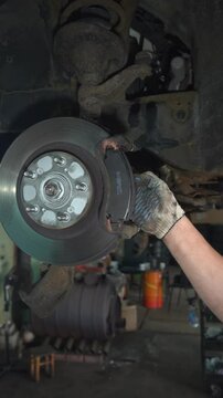 Auto mechanic installs brake pads. Car brake system repair.