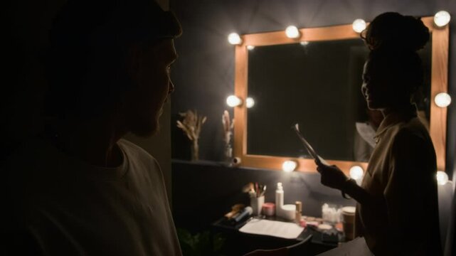Tilt-up shot of two stand-up artists getting ready for their performances in small dimly lit dressing room