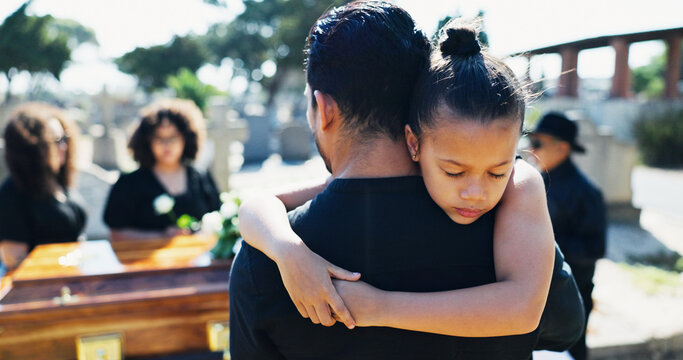 Child, hug or father in graveyard, compassion or burial for death, support or mourning with coffin. Girl, depressed or sad kid in cemetery for grief, loss or embrace with dad, crying and sympathy