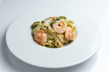 Tagliatelle with prawns and zucchini on white plate
